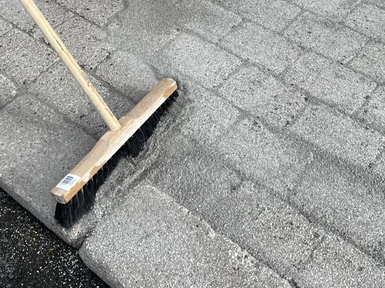 Ny fogsand borstas ner i fogarna på ren marksten
